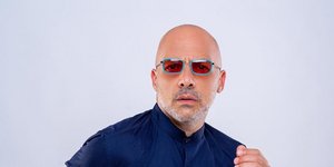 Ο Νίκος Μουτσινάς με μπλε πουκάμισο και γυαλιά