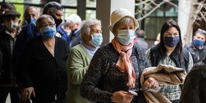 Ουρουγουανοί κάθονται σε ουρά φορώντας μάσκας