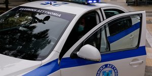Αστυνομικός στη θέση οδηγού σε περιπολικό με την πόρτα ανοιχτή