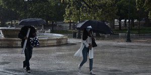 Πεζοί με ομπρέλες περπατούν στην βροχή