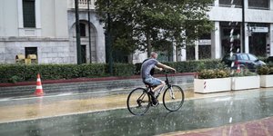 Ποδηλάτης στο κέντρο της Αθήνας με βροχή