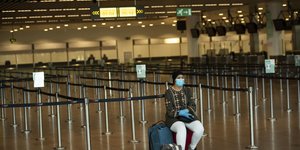 Γυναίκα κάθεται στη βαλίτσα της στο άδειο αεροδρόμιο των Βρυξελλών