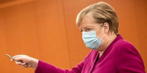 Η καγκελάριος Άνγκελα Μέρκελ με μάσκα και φούξια ταγέρ