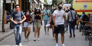 Πολίτες περπατούν με μάσκα για τον κορωνοϊό