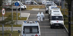 Προσωπικό νοσοκομείου στη Μόσχα με στολή και μάσκα σε προαύλιο χώρο με ασθενοφόρα