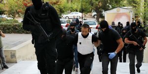 Αστυνομικοί συνοδεύουν μέλος της Ομάδας Λαϊκών Αγωνιστών στην ΓΑΔΑ