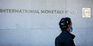 Γυναίκα περνά έξω από το ΔΝΤ φορώντας μάσκα