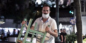 Εργαζόμενος σε εστιατόριο μαζεύει καρέκλες