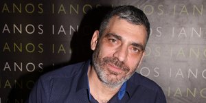 Ο Γιάννης Σερβετάς με μπλε πουκάμισο υπογράφει βιβλίο