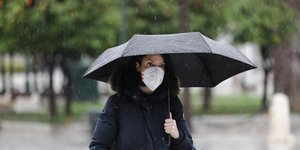 Γυναίκα με μαύρη ομπρέλα και μάσκα