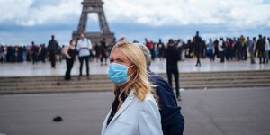 Γυναίκα με μάσκα μπροστά από τον πύργο του Αϊφελ 