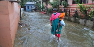 Γυναίκα κρατά αγκαλιά το παιδί της σε πλημμύρες στην Ινδία