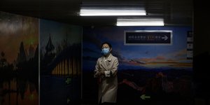 Κινέζα σε τούνελ με καπαρντίνα και μάσκα