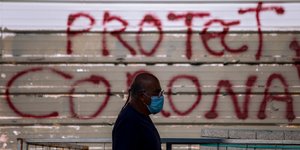 Ισραηλινός περνά μπροστά από τοίχο με σύνθημα για τον κορωνοϊό