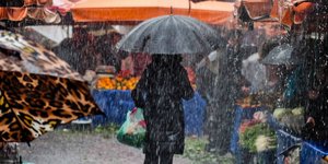 Καιρός: Μια γυναίκα περπατά με ομπρέλα σε λαϊκή αγορά