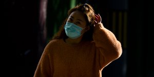 Κινέζα με μάσκα ξύνει το κεφάλι της