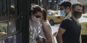 Πολίτες βγαίνουν από λεωφορείο, φορώντας μάσκες