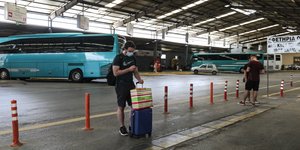 Επιβάτης περιμένει μπροστά από λεωφορεία του ΚΤΕΛ