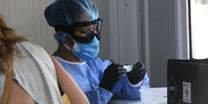 Γυναίκα με στολή και μάσκα πραγματοποιεί τεστ κορωνοϊού στην Αττική