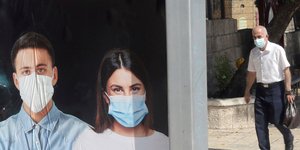 Ηλικιωμένος περνά δίπλα από φωτογραφία με μάσκες