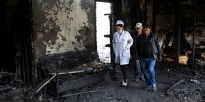 Ανθρωποι περπατούν τα ερείπια σπιτιού που καταστράφηκε από πυρά στο Ναγκόρνο Καραμπάχ