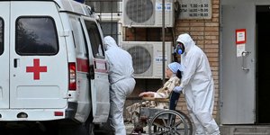 Επαγγελματίες υγείας με στολή και μάσκα για τον κορωνοϊό έξω από νοσοκομείο στη Μόσχα