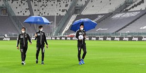 Παίκτες της Γιουβέντους κάνουν βόλα εντός γηπέδου κρατώντας ομπρέλες