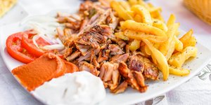 Πιάτο με τραγανό γύρο χοιρινό με πατάτες, ντομάτα και τζατζίκι