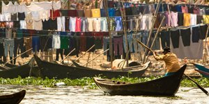 βαρκάρης σε ποταμό Μπαγκλαντές απλωμένα πολύχρωμα ρούχα  