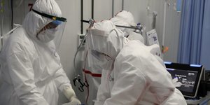 τρεις γιατροι με στολές κοιτουν κατω 