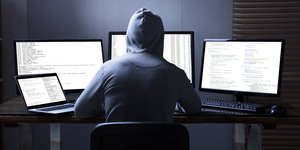 Ενας χάκερ με κουκούλα μπροστά από υπολογιστή