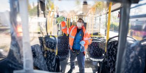 Υπάλληλος καθαρίζει λεωφορείο στη Γερμανία, φορώντας μάσκα