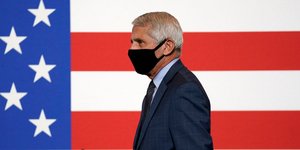 Ο λοιμωξιολόγος των ΗΠΑ, Άντονι Φάουτσι με μάσκα μπροστά από μια σημαία της χώρας