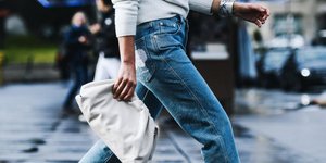 Γυναίκα φοράει τζιν και κρατάει λευκή τσάντα