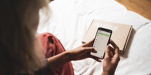 Γυναίκα κρατά κινητό στο κρεβάτι
