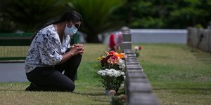 Γυναίκα γονατίζει μπροστά σε μνημείο νεκρού