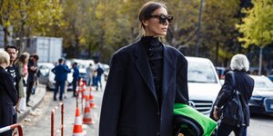 Γυναίκα με πουλόβερ και σακάκι στο δρόμο κρατά τσάντα 