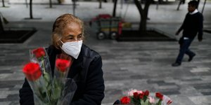 Γυναίκα με μάσκα στο Μεξικό κρατά τριαντάφυλλα