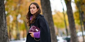 Μια καστανή γυναίκα κρατάει μια μοβ τσάντα