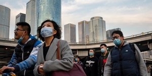 Κινέζοι περπατούν φορώντας μάσκες