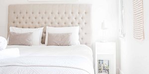 Κρεβατοκάμαρα διαμερίσματος με λευκό κομοδίνο και φωτιστικό