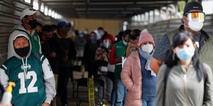 Μεξικανοί στέκονται σε ουρά φορώντας μάσκας