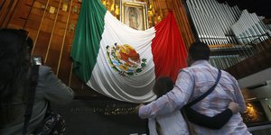 Οικογένεια κοιτάζει εικόνισμα και σημαία Μεξικού