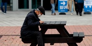 Ηλικιωμένος με μάσκα κάθετε σε παγκάκι στη Νότια Κορέα