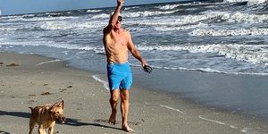 Ο Γκρεγκ Νόρμαν με τον σκύλο του κάνουν βόλτα σε μια παραλία