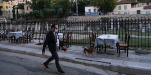 Πεζός με σκύλο περνά δίπλα από τραπέζια στο Θησείο