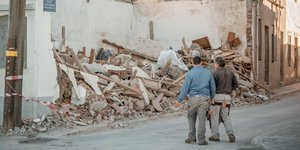 δύο άνδρες κοιτούν τα ερείπια που άφησε ο σεισμός στη Σάμο