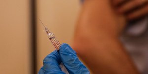 Νοσοκόμα με γάντια κρατά σύριγγα με το υπό έρευνα εμβόλιο για τον κορωνοϊό