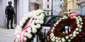 Αστυνομικός πίσω από καταθετημένα στεφάνια για νεκρό από την επίθεση στη Βιέννη