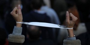 Διαδηλωτής στη Μασαλία της Γαλλίας με τα χέρια περασμένα σε μια μάσκα, που μοιάζει με χειροπέδα